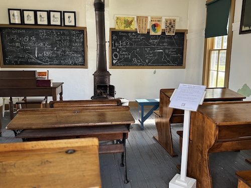 Inside of Peters' School showing two blackboards, wood stove, desks.