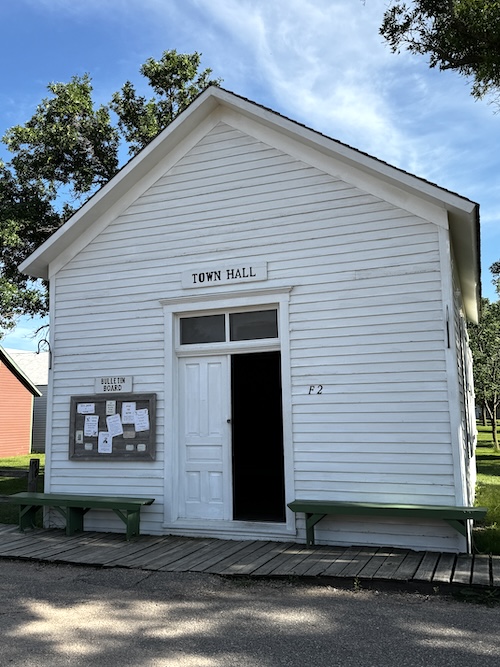 One story plain white building with sign saying Town Hall.
