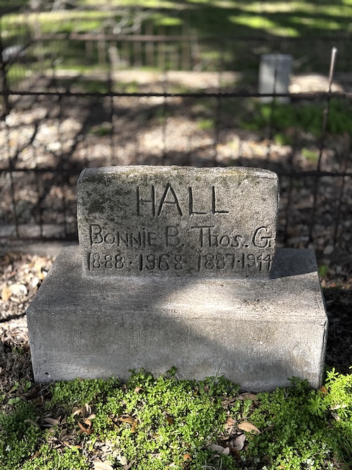 Image of plain headstone with unmarked foundation with upright stone on top with name simply engraved.